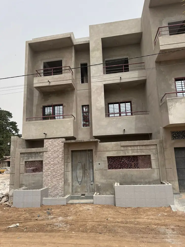 Photo du chantier : façade principale avec balcons, porte d'entrée et parement pierre